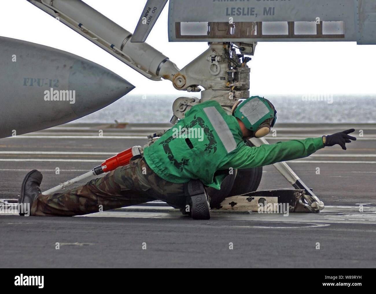 A Navy flight deck crewman brings an aircraft into launch position on ...