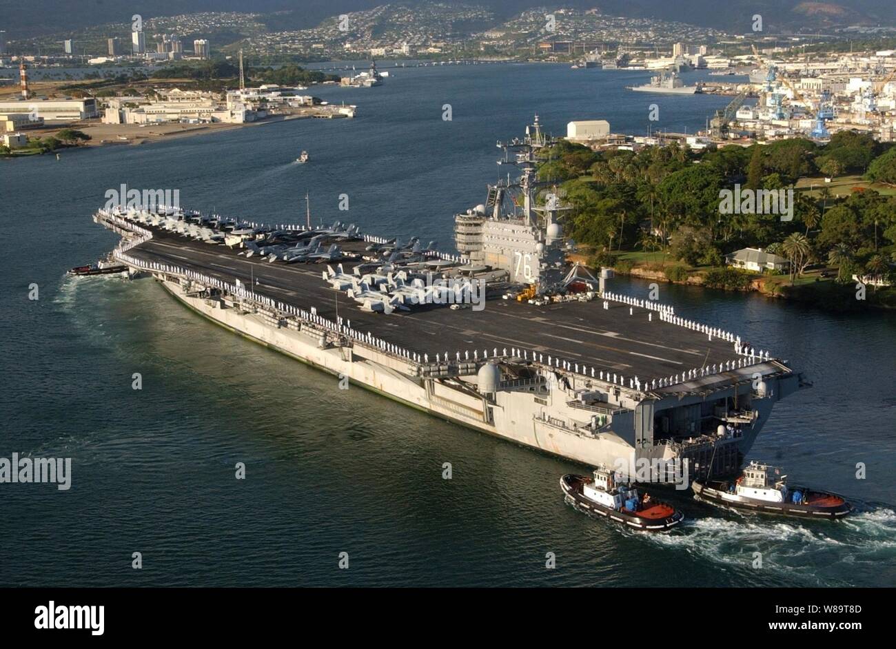 The aircraft carrier USS Ronald Reagan (CVN 76) is aided by harbor tugs as it enters Pearl Harbor, Hawaii, for a port visit on June 28, 2006.  Reagan and embarked Carrier Air Wing 14 are on a regularly scheduled deployment conducting maritime security operations. Stock Photo