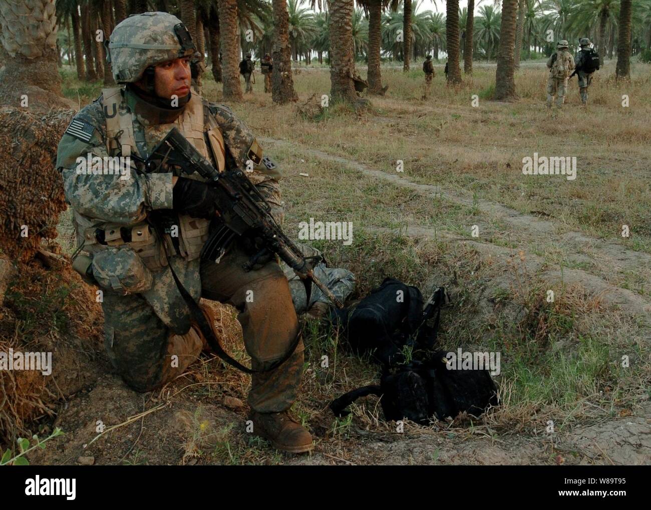 U.S. Army Staff Sgt. Danny Jimenez kneels on one knee as he provides perimeter security for his fellow soldiers during an air-assault raid on a suspected insurgent sanctuary in Mushada, Iraq, on June 23, 2006.  Jimenez is from the 1st Battalion, 66th Armor Regiment, 1st Brigade Combat Team, 4th Infantry Division. Stock Photo