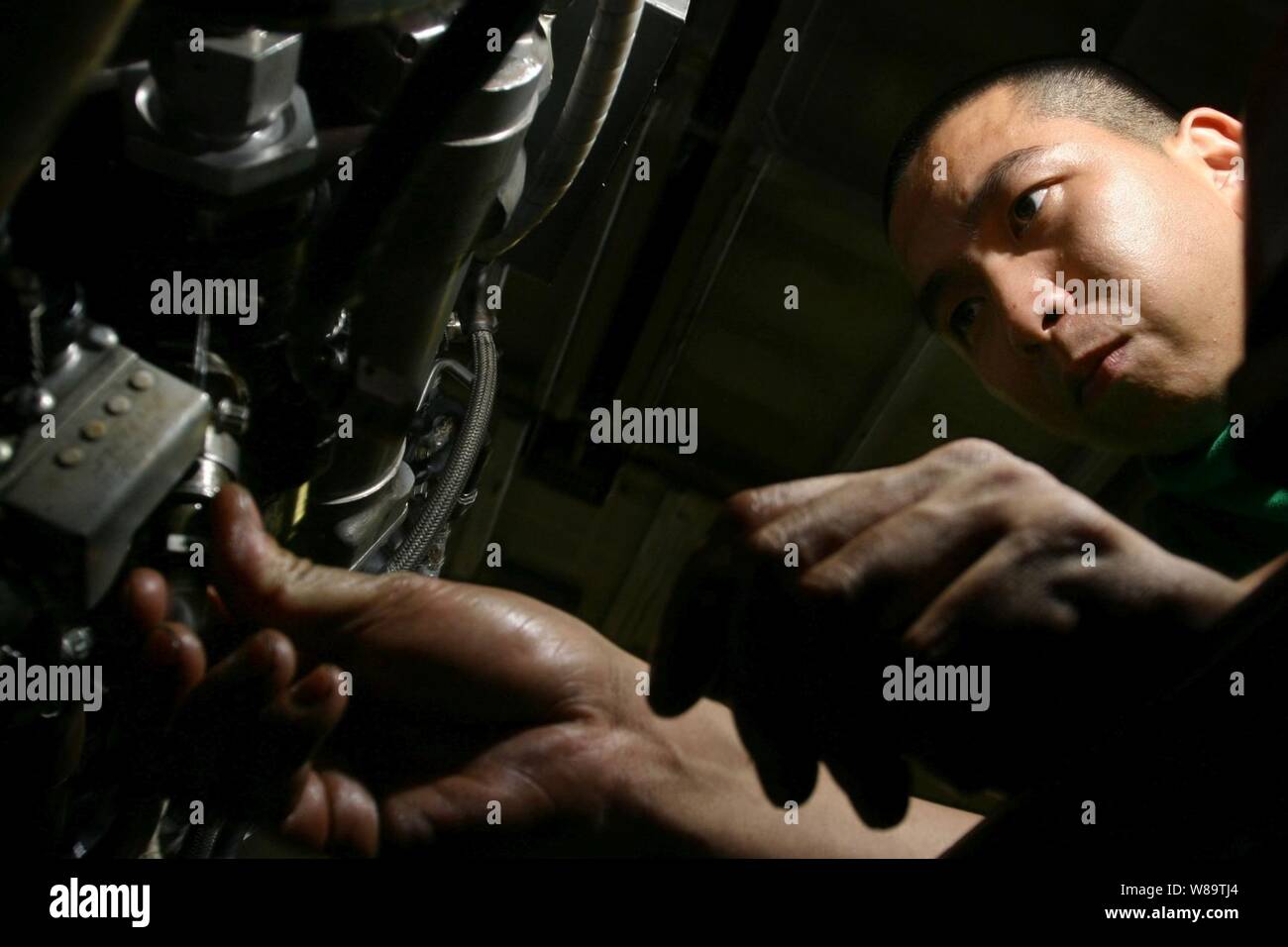 Petty Officer 2nd Class Christian Tan prepares a J52 jet engine for installation into an EA-6B Prowler aircraft in the hangar deck of the aircraft carrier USS Kitty Hawk (CV 63) as the ship operates in the waters off southern Japan on Nov. 3, 2006.  Tan is a U.S. Navy aviation machinist's mate onboard the carrier. Stock Photo