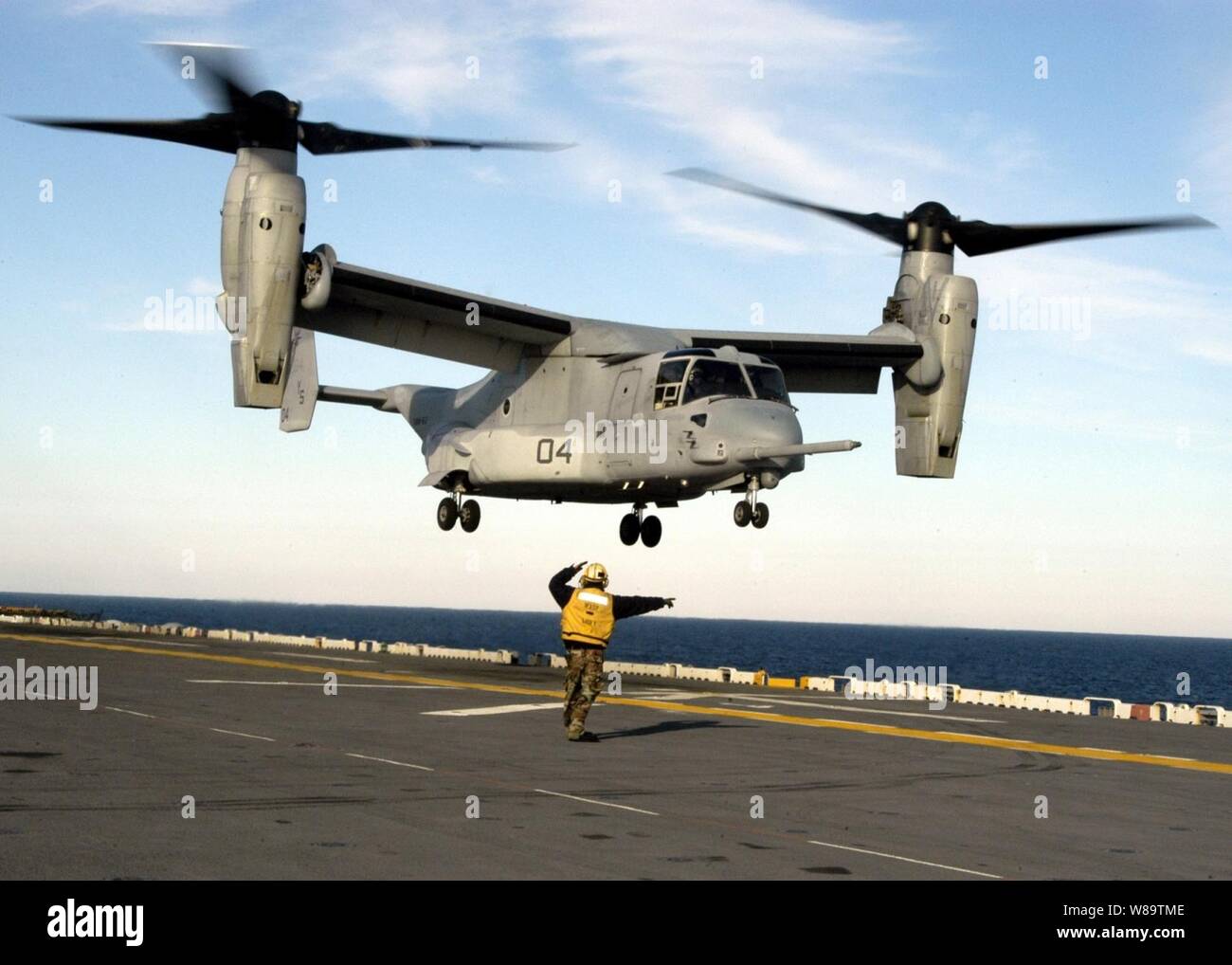A flight deck crewman directs the crew of a U.S. Marine Corps CV-22 Osprey tilt rotor aircraft as they practice touch and go landings on the flight deck of the USS Wasp (LHD 1) as the ship operates in the Atlantic Ocean on Dec. 6, 2006.  The Osprey is from Marine Medium Tiltrotor Squadron 162 and is working on deck landing qualifications. Stock Photo