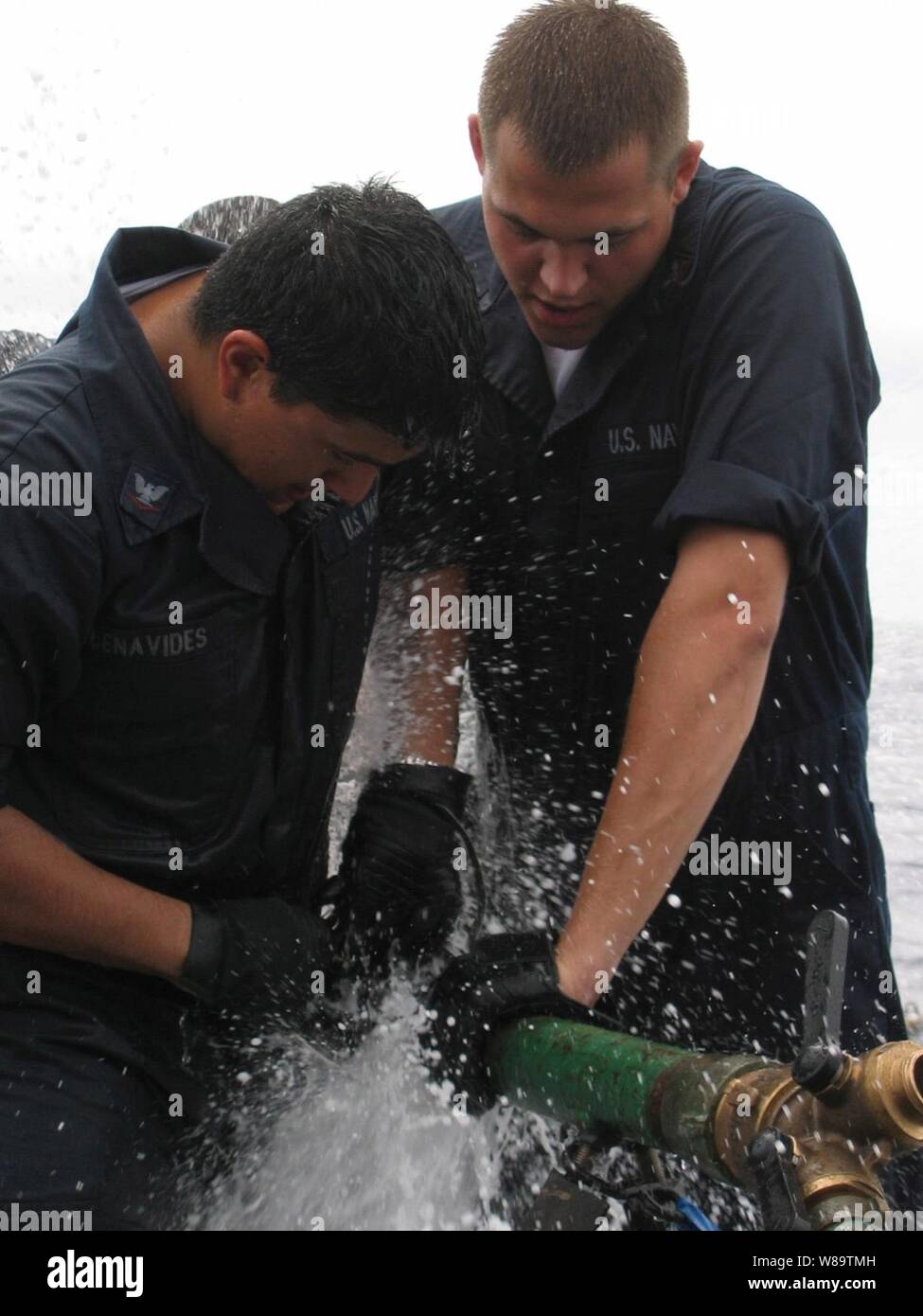 U.S. Navy Petty Officer 2nd Class Michael Murphy (right) and Petty Officer 3rd Class Joshua Benavides try to stop the leak as they compete in the pipe-patching event during the Damage Control Olympics aboard the guided-missile frigate USS Robert G. Bradley (FFG 49) on Dec. 2, 2006.  Murphy and Benavides are Navy damage controlmen.   The Bradley is deployed to the Eastern Pacific in support of counter-narcoterrorism operations. Stock Photo