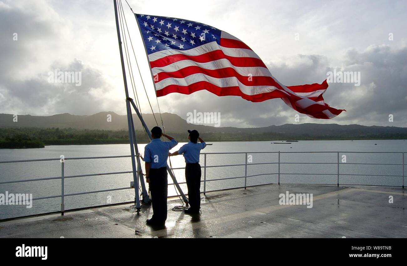U.S. Navy sailors salute the ensign after bringing it to half-staff in honor of Navy veteran and former President Gerald R. Ford aboard the submarine tender USS Frank Cable (AS 40) in Apra Harbor, Guam, on Jan. 1, 2007. Stock Photo