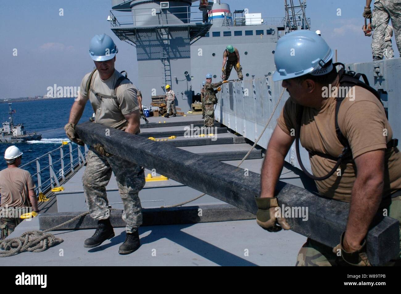 U.S. Army Pfc. Anthony Phillips (left) and U.S. Navy Petty Officer 2nd Class Lawrence Gonzalez, carry a wooden beam to support a dunnage box during the Humanitarian Support over the Shore 2007 in Puerto Quetzal, Guatemala, on Feb. 6, 2007.  Approximately 1,300 U.S. servicemen and women representing the Navy, Army, National Guard, and Reserve forces are participating the simulated disaster response exercise that involves transporting equipment from two engineer task forces.  Phillips is attached to the 567th Inlet Cargo Transportation Company while Gonzalez is attached to Navy Cargo Handling Ba Stock Photo