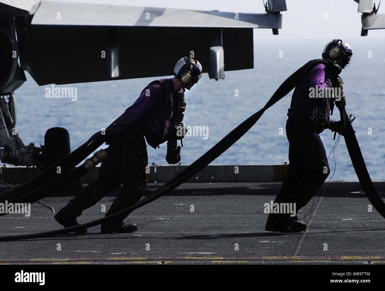 U.S. Navy sailors from the air department's flight deck aircraft handling division heave fuel hoses out to refuel aircraft aboard the aircraft carrier USS John C. Stennis (CVN 74) as the ship operates in the Arabian Sea on March 8, 2007. Stock Photo