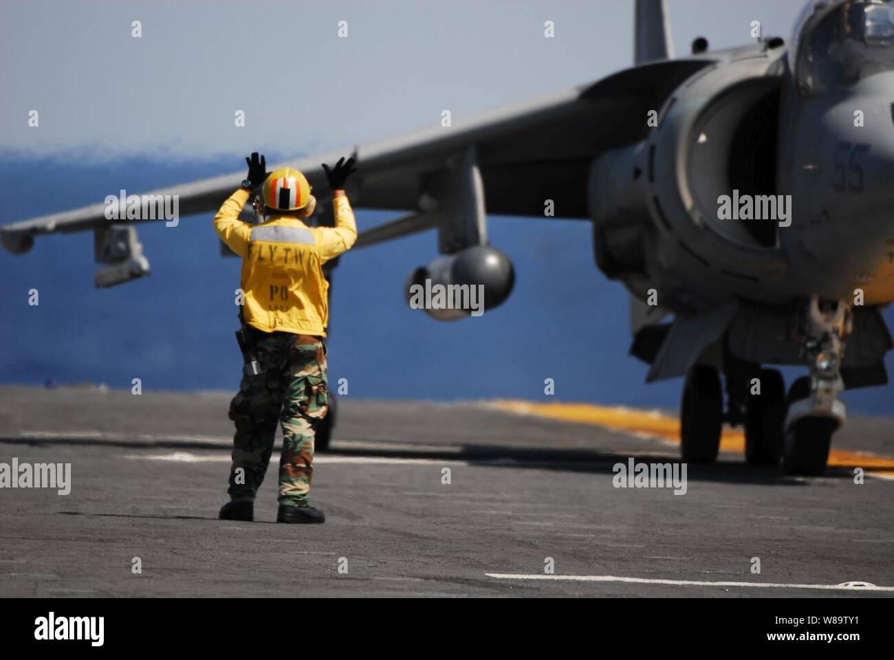 U.S. Navy Petty Officer 2nd Class Charles Imanil directs an AV-8B Harrier II aircraft onto the flight deck of the amphibious assault ship USS Kearsarge (LHD 3) on May 19, 2007.  The Kearsarge and embarked Marine Medium Helicopter Squadron 261 are participating in a composite unit training exercise in the Atlantic Ocean.  Imanil is a U.S. Navy Aviation Boatswainís Mate Handling. Stock Photo