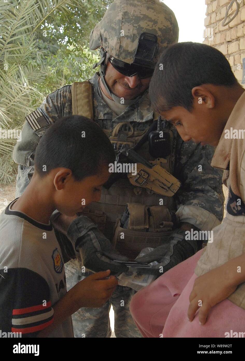 A U.S. Army soldier from Echo Company, 96th Civil Affairs Battalion shows pictures of his children to Iraqi children on Aug. 1, 2007.  Echo Company is attached to the 4th Stryker Brigade Combat Team, 2nd Infantry Division. Stock Photo