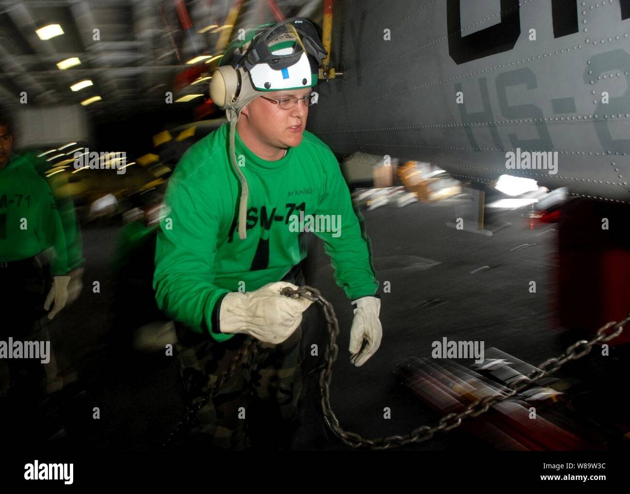 U.S. Navy Airman Cody Humphrey attaches tie-down chains to an SH-60F Seahawk helicopter in the hangar bay of the aircraft carrier USS Abraham Lincoln (CVN 72) while under way in the Pacific Ocean on July 30, 2007. Stock Photo