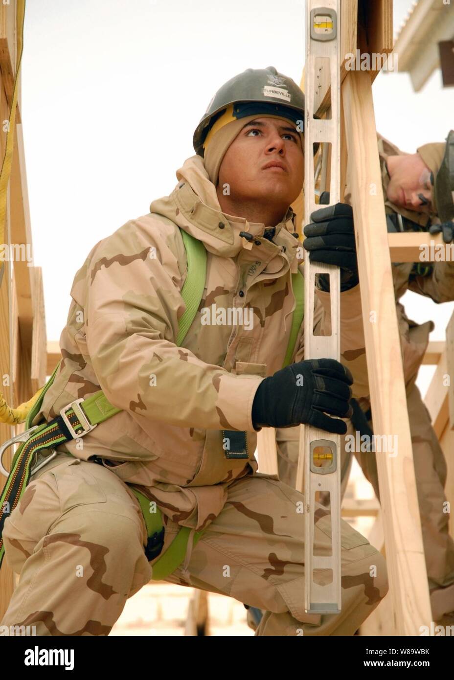 U.S. Navy Seabee Petty Officer 3rd Class Adam Turbeville checks the plumb of a truss while working on the construction of a fellowship hall at Camp Ramadi, Iraq, on Dec. 20, 2007.  The hall will be used to host conferences, celebrations and worship services, and will also serve as a place for service members to relax.  Turbeville is a Navy Builder assigned to Naval Mobile Construction Battalion 1. Stock Photo