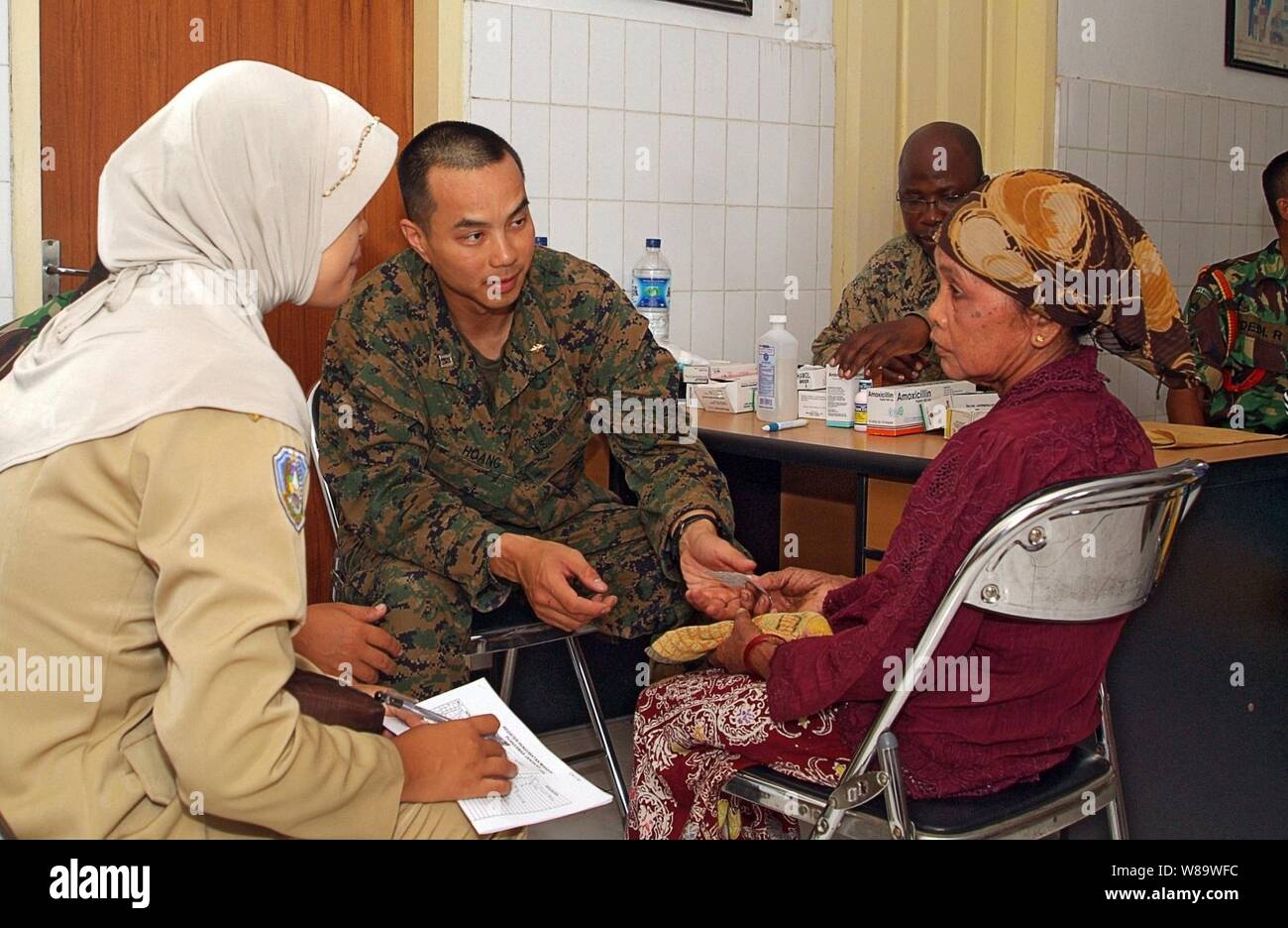 U.S. Navy Lt. Thomas Hoang (2nd from left) speaks with a patient during a medical and dental civic action project in Puskesmas Jangkar, Indonesia, on March 12, 2008.  U.S. Marines and sailors from the 31st Marine Expeditionary Unit and members of the Indonesian armed forces are conducting the project to increase humanitarian assistance and disaster relief response capabilities, improve interoperability and continue professional relationships between the two militaries. Stock Photo