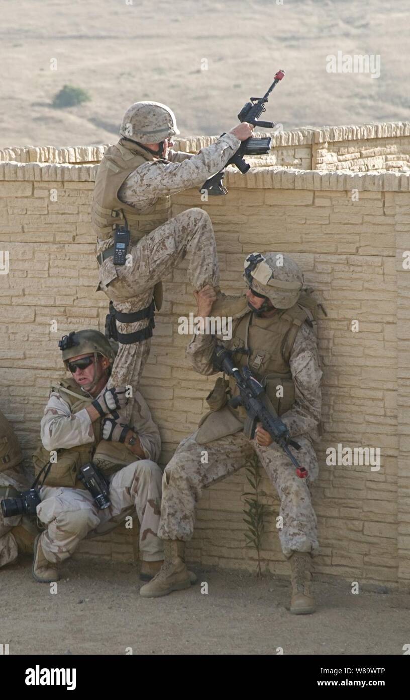 U.S. Navy Petty Officer 2nd Class Scott Taylor (left) and an unidentified Marine help another Marine scale a wall during a training exercise at Marine Corps Base Camp Pendleton, Calif., on Aug 12, 2008.  The training is designed to simulate urban combat situations that the Marines will face in future deployments.  The Marines are assigned to Echo Company, 2nd Battalion, 1st Marine Division. Stock Photo