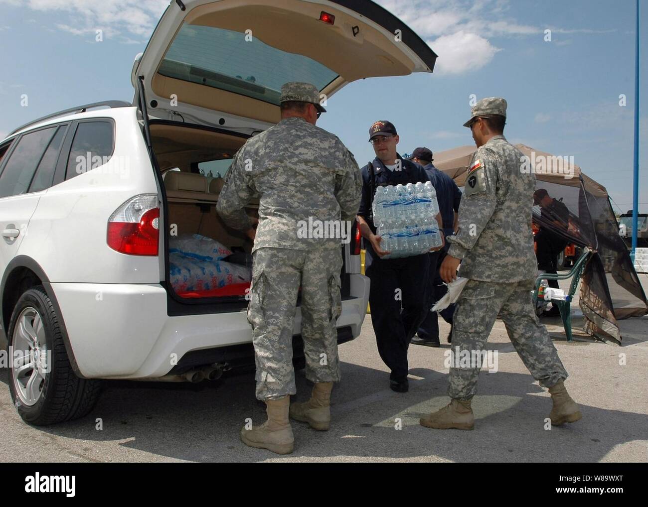 U.S. Navy Petty Officer 1st Class Roberto Diesta, assigned to the amphibious assault ship USS Nassau (LHA 4), and soldiers from the Texas Army National Guard load ice into a resident's vehicle during a disaster response mission in Galveston, Texas, on Sept. 18, 2008.  The Nassau is anchored off the coast of Galveston, Texas, to render assistance to other military organizations and civil authorities deployed in support of Hurricane Ike disaster relief efforts. Stock Photo
