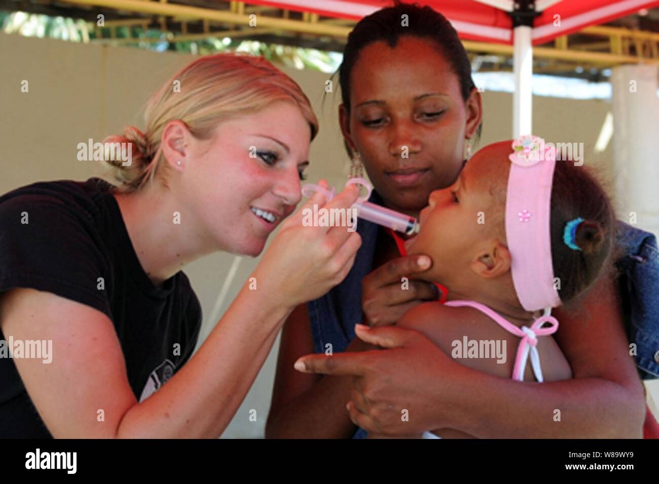 U.S. Air Force Senior Airman Alex Olson, an augmentee embarked aboard the amphibious assault ship USS Kearsarge (LHD 3), administers de-worming medication to a young patient during medical operations at the Las Calderas Naval Base in Dominican Republic on Oct. 10, 2008. The Kearsarge is supporting the Caribbean phase of Continuing Promise 2008, an equal-partnership mission involving the United States, Canada, the Netherlands, Brazil, France, Nicaragua, Colombia, Dominican Republic, Trinidad and Tobago and Guyana. Stock Photo