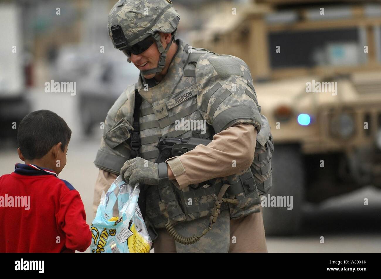 U.S. Air Force Airman 1st Class Justin Iverson, assigned to Detachment 3, 732nd Expeditionary Security Forces Squadron, attached to the 1st Brigade Combat Team, 4th Infantry Division, hands out candy to Iraqi children during a patrol in the Doura district of Baghdad, Iraq, on Nov. 22, 2008. Stock Photo