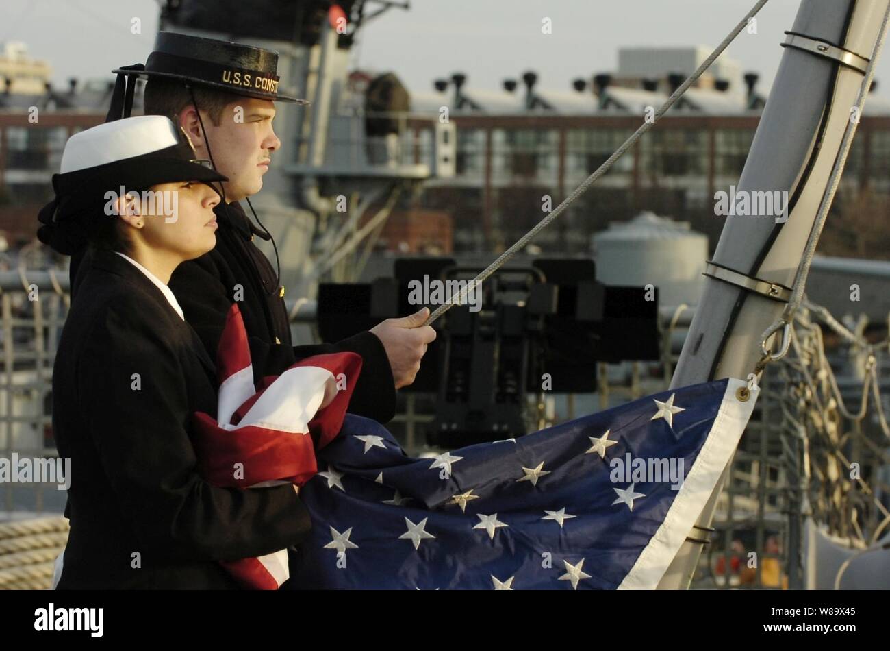 U.S. Navy Chief Quartermaster Stephanie Kotatis (left) and Boatswainís Mate Seaman Dustin Foster, a sailor assigned to the USS Constitution, stand by to commence raising the colors aboard the littoral combat ship USS Freedom (LCS 1) at Boston, Mass., on Dec. 6, 2008.  The Freedom is the first of two littoral combat ships designed to operate in shallow water environments to counter threats in coastal regions. Stock Photo