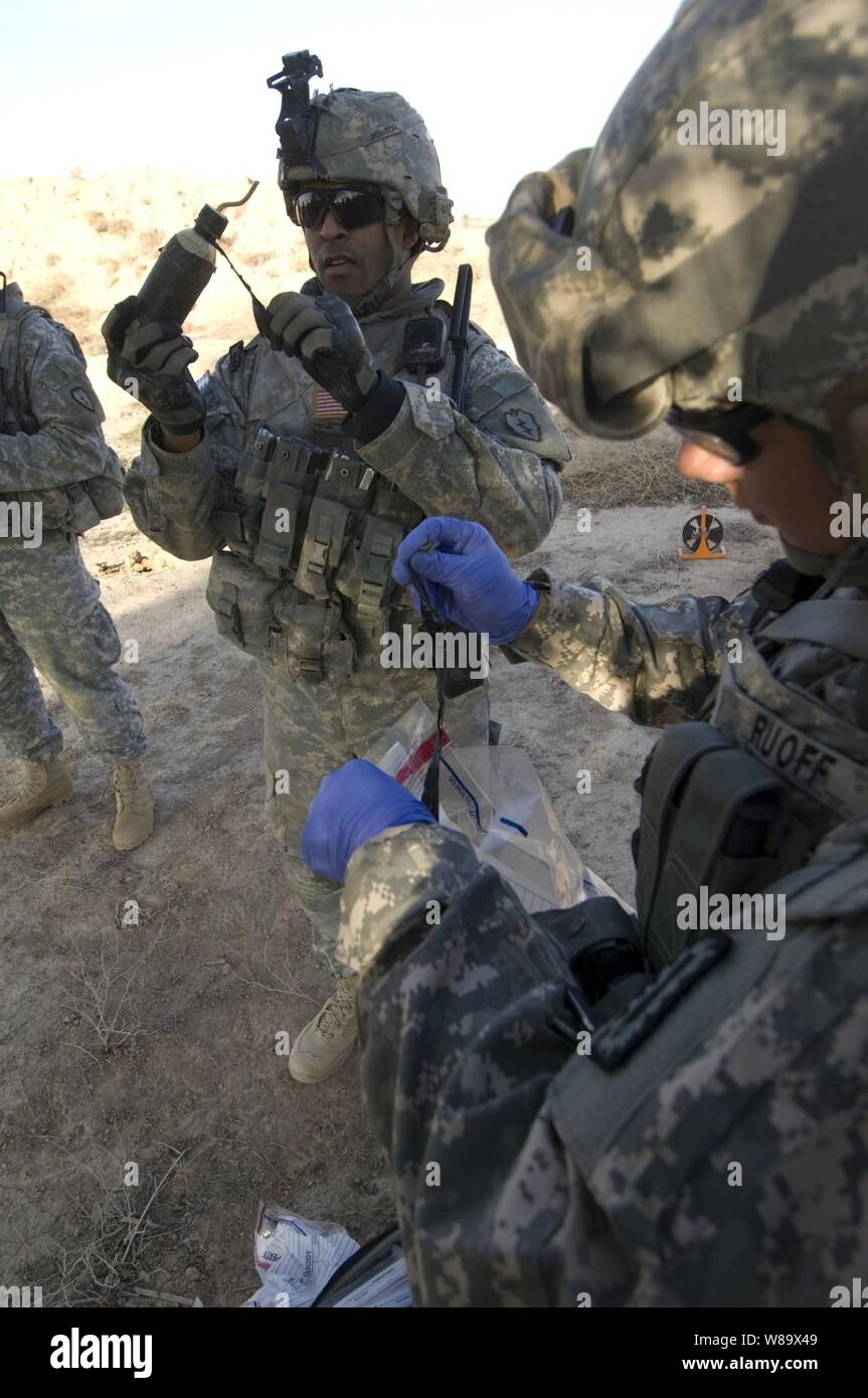 U.S. Army Staff Sgt. Lashawn Lenore (2nd from right) and U.S. Navy Petty Officer 2nd Class Richard Ruoff take samples from items found in a weapons cache in Baqouba, Iraq, on Jan. 3, 2009.  U.S. soldiers from the Chemical, Biological, Radiation and Nuclear Weapons Intelligence Team Platoon, Brigade Troops Battalion, 1st Stryker Brigade Combat Team, 25th Infantry Division are moving to exploit a weapons cache found by fellow 25th Infantry Division soldiers while conducting a patrol. Stock Photo