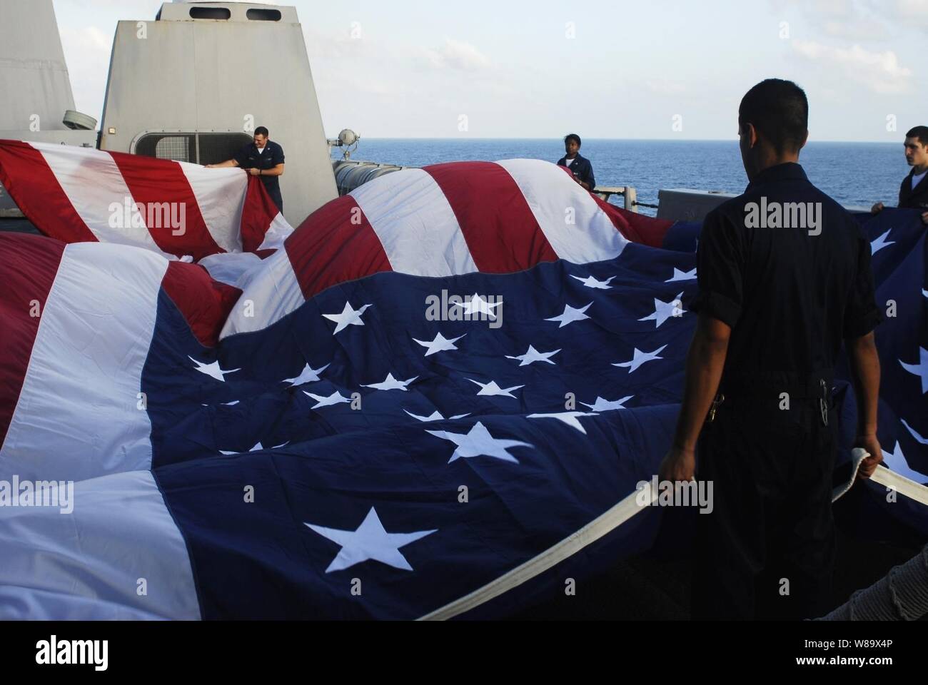 U.S. Navy sailors aboard the amphibious transport dock ship USS San Antonio (LPD 17) fold a 30-foot by 60-foot American flag while in the Gulf of Aden on Jan. 12, 2009.  The San Antonio is the command ship for Combined Task Force 151.  Combined Task Force 151 is a multi-national task force conducting counter-piracy operations in and around the Gulf of Aden, Arabian Sea, Indian Ocean and Red Sea.  It was established to create a lawful maritime order and develop security in the maritime environment. Stock Photo