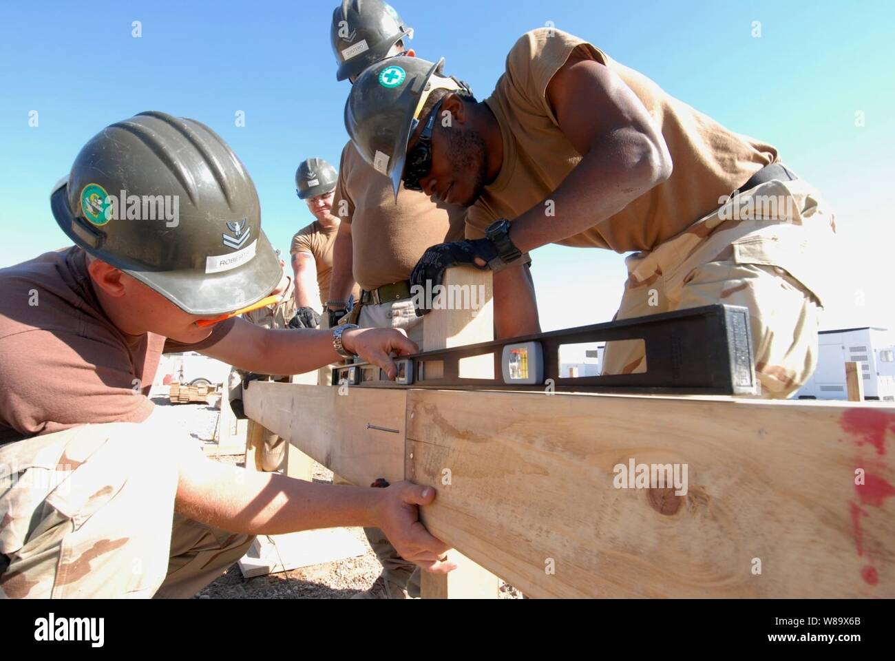 U.S. Navy Petty Officer 2nd Class Jeffrey Roberts uses a level to ensure a frame board is aligned properly as Seaman Michael Joseph holds it in place while making improvements to a patrol base in Mahawil, Iraq, on Feb. 4, 2009.  The Navy Seabees are from Amphibious Construction Battalion 2. Stock Photo
