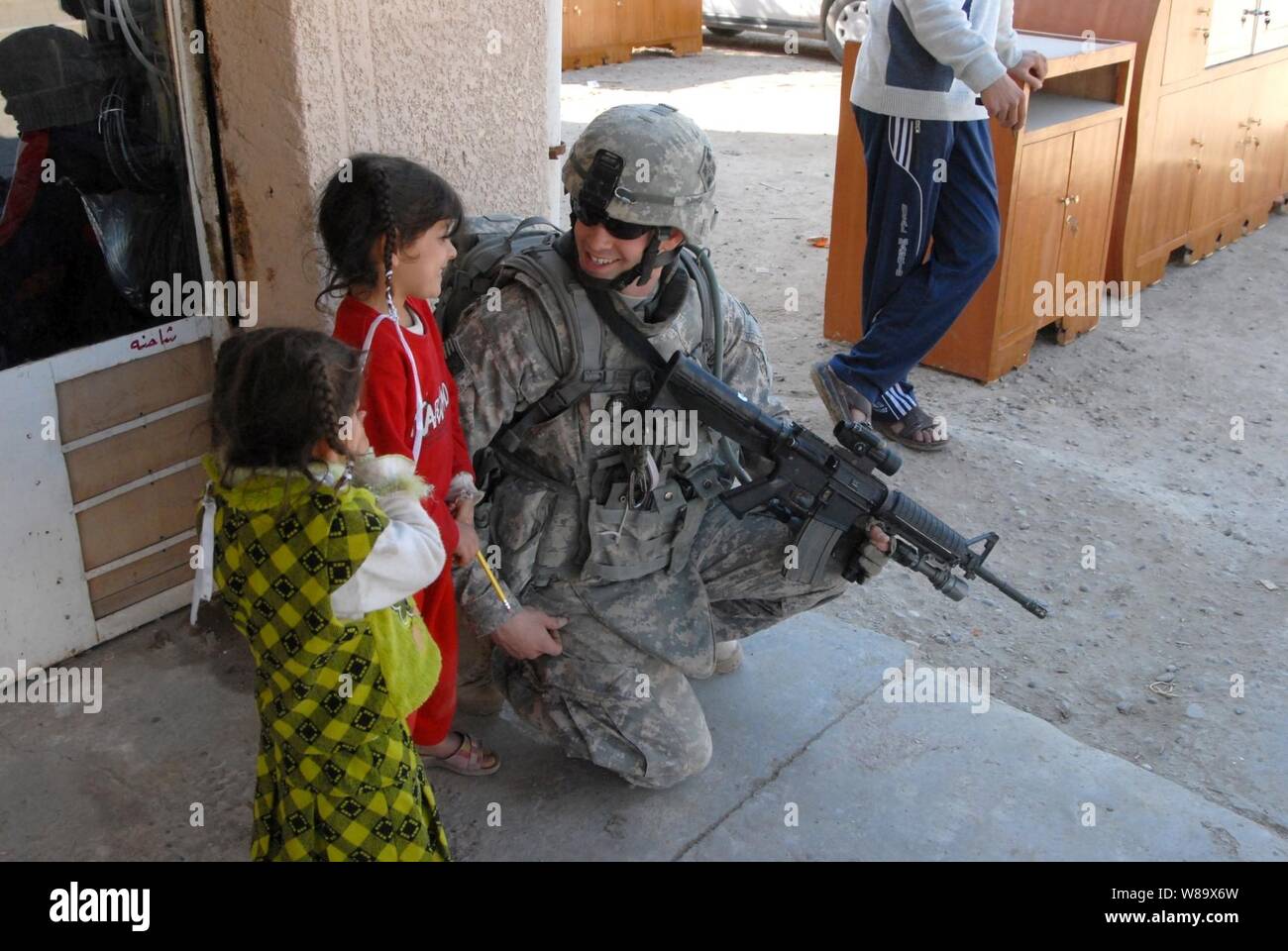 U.S. Army Pfc. Toby Barnes of 2nd Brigade Combat Team, 4th Infantry Division talks to two Iraqi girls during a joint patrol with Iraqi police to conduct post-election surveys in Iman, Iraq, on Feb. 3, 2009. Stock Photo