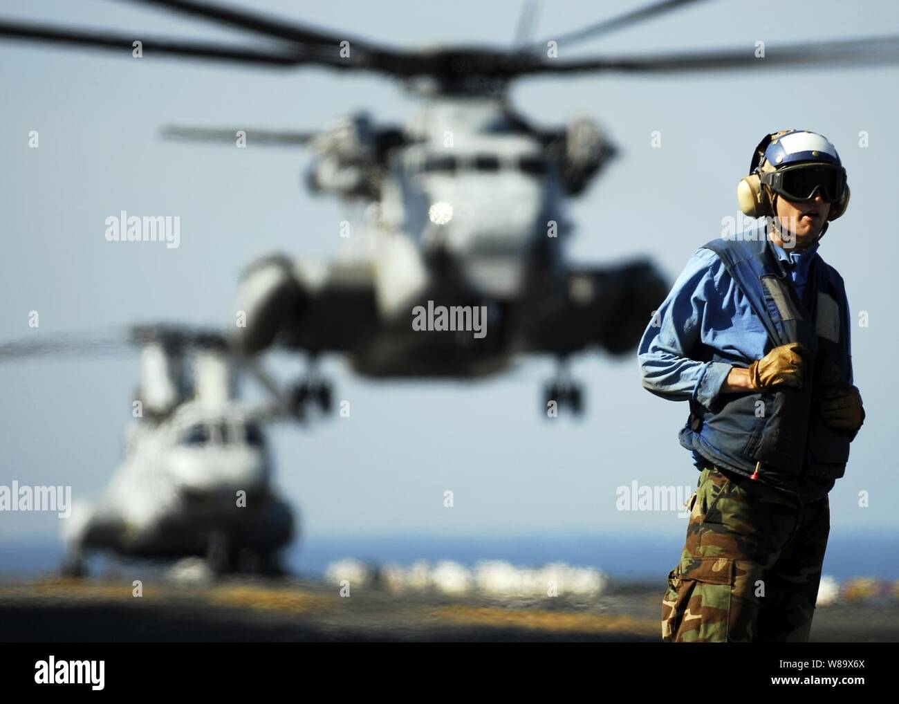 U.S. Navy Airman Patrick Neimeyer stands on the flight deck of the amphibious assault ship USS Essex (LHD 2) as a CH-53E Sea Stallion helicopter lands during exercise Cobra Gold 09 in the Gulf of Thailand on Feb. 15, 2009.  Cobra Gold is an annual joint-combined exercise conducted by military forces of the United States and Thailand to strengthen ties and prepare for possible contingencies in the region. Stock Photo