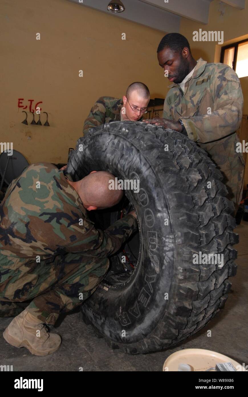 U.S. Army Sgt. Raymond Averesch (left), Pfc. Curtis Lacher (center) and Spc. Cedrick Griffin, with the Military Transition and Training Team, assemble a wheel for a mine-resistant, ambush-protected vehicle in Kadhimiya, Iraq, on Feb. 23, 2009. Stock Photo