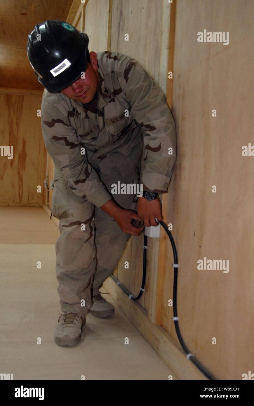 U.S. Navy Petty Officer 3rd Class Joe Nichols from Amphibious Construction Battalion 2 tests the electrical outlets during a completion-of-work tour through the new barracks and dining facility at Patrol Base Mahawil, Iraq, on March 2, 2009. Stock Photo
