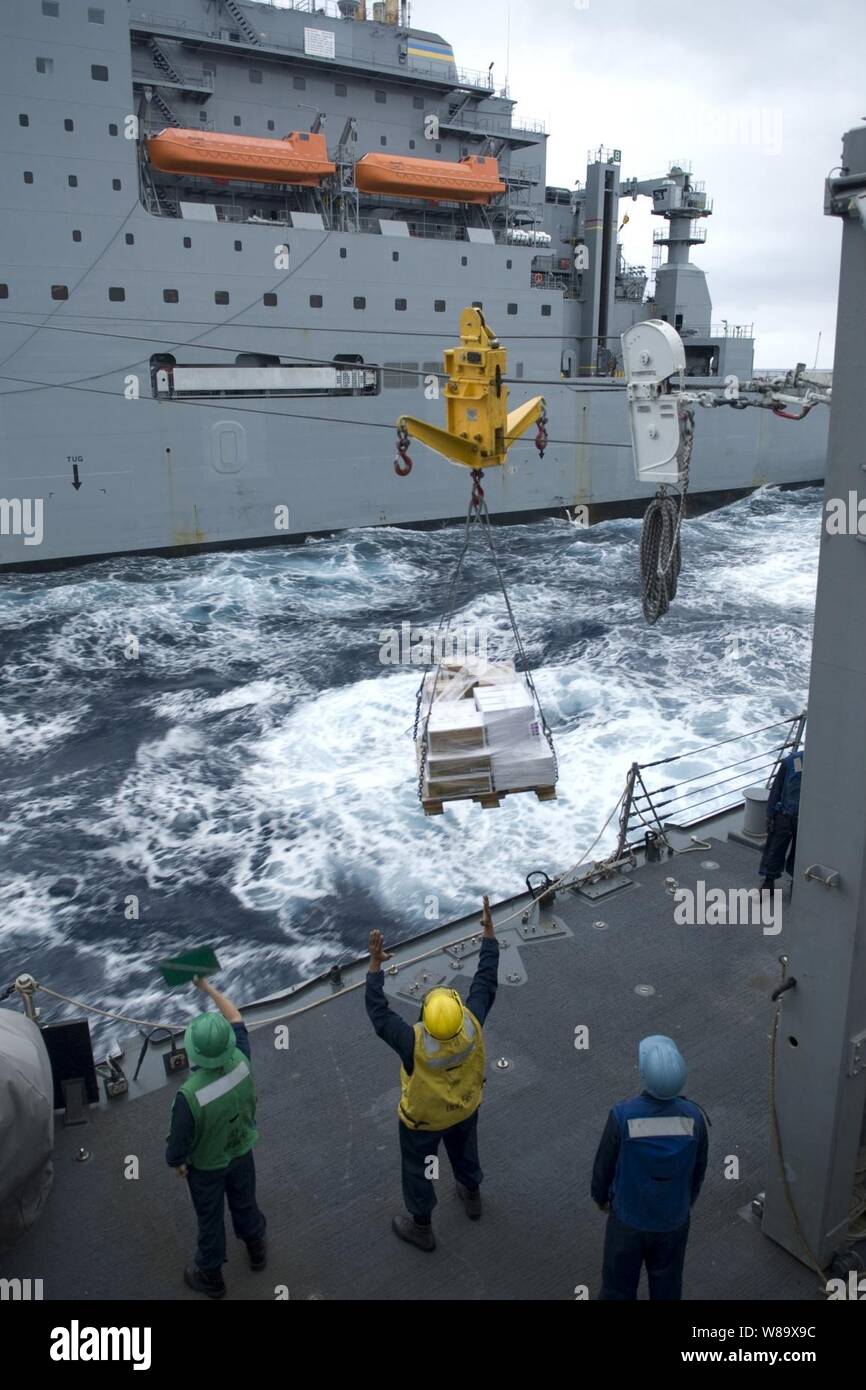 U.S. Navy sailors aboard the guided-missile destroyer USS John S. McCain (DDG 56) receive a pallet of supplies from Military Sealift Command underway replenishment ship USNS Alan Shepard (T-AKE 3) in the Pacific Ocean on March 4, 2009.  The McCain is one of seven Arleigh Burke-class destroyers assigned to Destroyer Squadron 15 and is permanently forward deployed to Yokosuka, Japan. Stock Photo