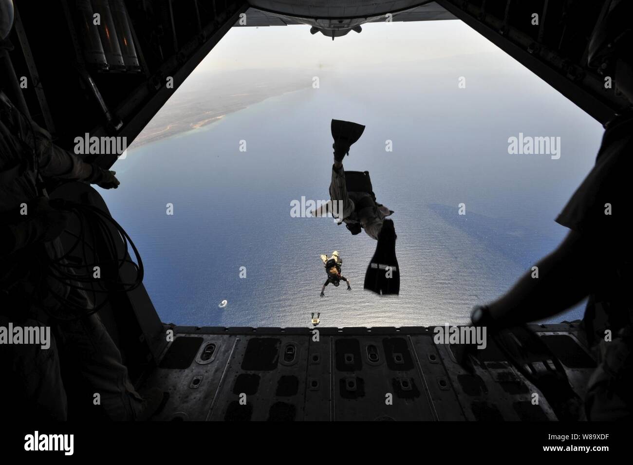 A U.S. Air Force pararescueman from the 82nd Rescue Squadron jumps out of an HC-130P Hercules aircraft during a training exercise in Djibouti on April 23, 2009.  The exercise consisted of transporting pararescuemen to their water jump, aerial refueling of a CH-53E Super Stallion helicopter, an assault landing on an unimproved runway and transfer/loading a simulated survivor from the CH-53E. Stock Photo