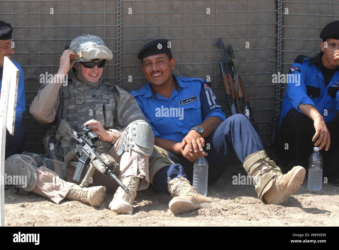 U.S. Air Force Senior Airman Miller, attached to the Rough Riders, 91st Battalion, Task Force Dragon, relaxes with a group of Iraqi policemen at a firing range in Mahmudiyah, Iraq, on April 23, 2009.  The Rough Riders are instructing Iraqi policemen how to safely aim and fire their weapons.  These policemen will be sent out to instruct other Iraqi police officers throughout the country. Stock Photo