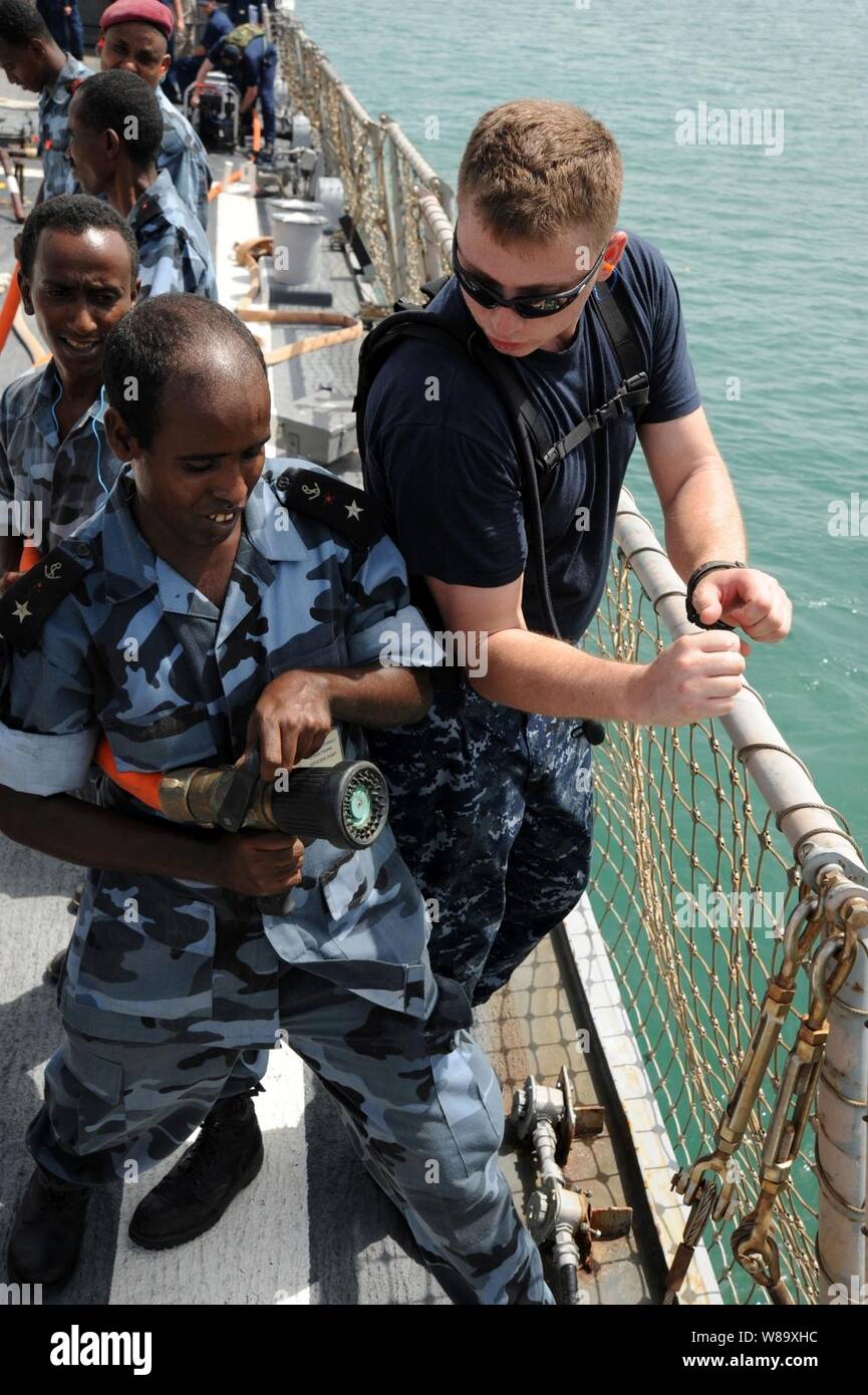 U.S. Navy Petty Officer 1st Class James Harry trains Djiboutian sailors in hose-handling techniques on the flight deck of the guided-missile destroyer USS Arleigh Burke (DDG 51) in Djibouti on June 11, 2009.  The Arleigh Burke is deployed as part of Africa Partnership Station, an international initiative developed by Naval Forces Europe and Naval Forces Africa to improve maritime security around the African continent. Stock Photo