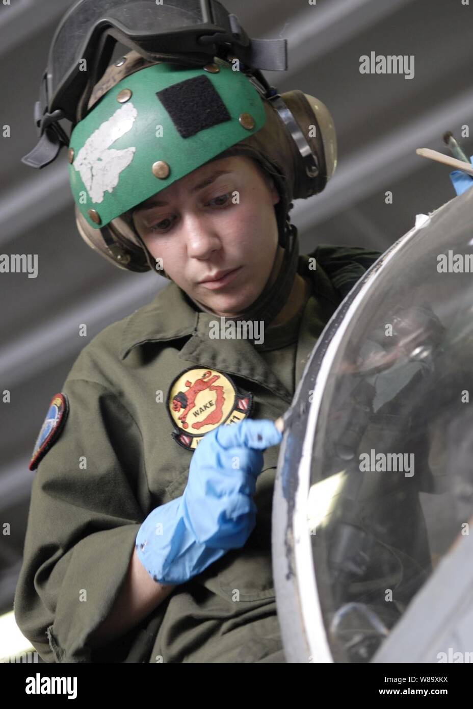 U.S. Marine Corps Cpl. Miranda Bouska, with Fixed Wing Marine Attack Squadron 211, and deployed to the amphibious assault ship USS Essex (LHD 2), applies sealant on the cockpit of a AV-8B Harrier aircraft in the ship's hanger bay while the ship is underway in the Coral Sea on July 11, 2009.  The Essex is the lead ship of the only forward-deployed expeditionary strike group and serves as the flagship for Combined Task Force 76, the Navy's only forward-deployed amphibious force command. Stock Photo