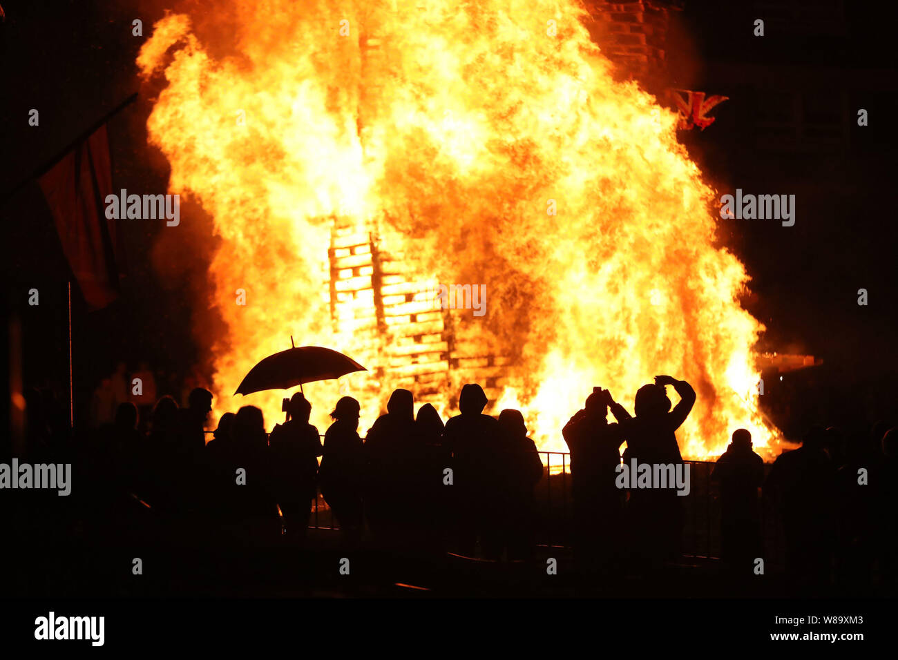 Crowds watch as a bonfire is lit in the New Lodge area of Belfast to mark the anniversary of the introduction of the controversial policy of internment without trial.. Stock Photo