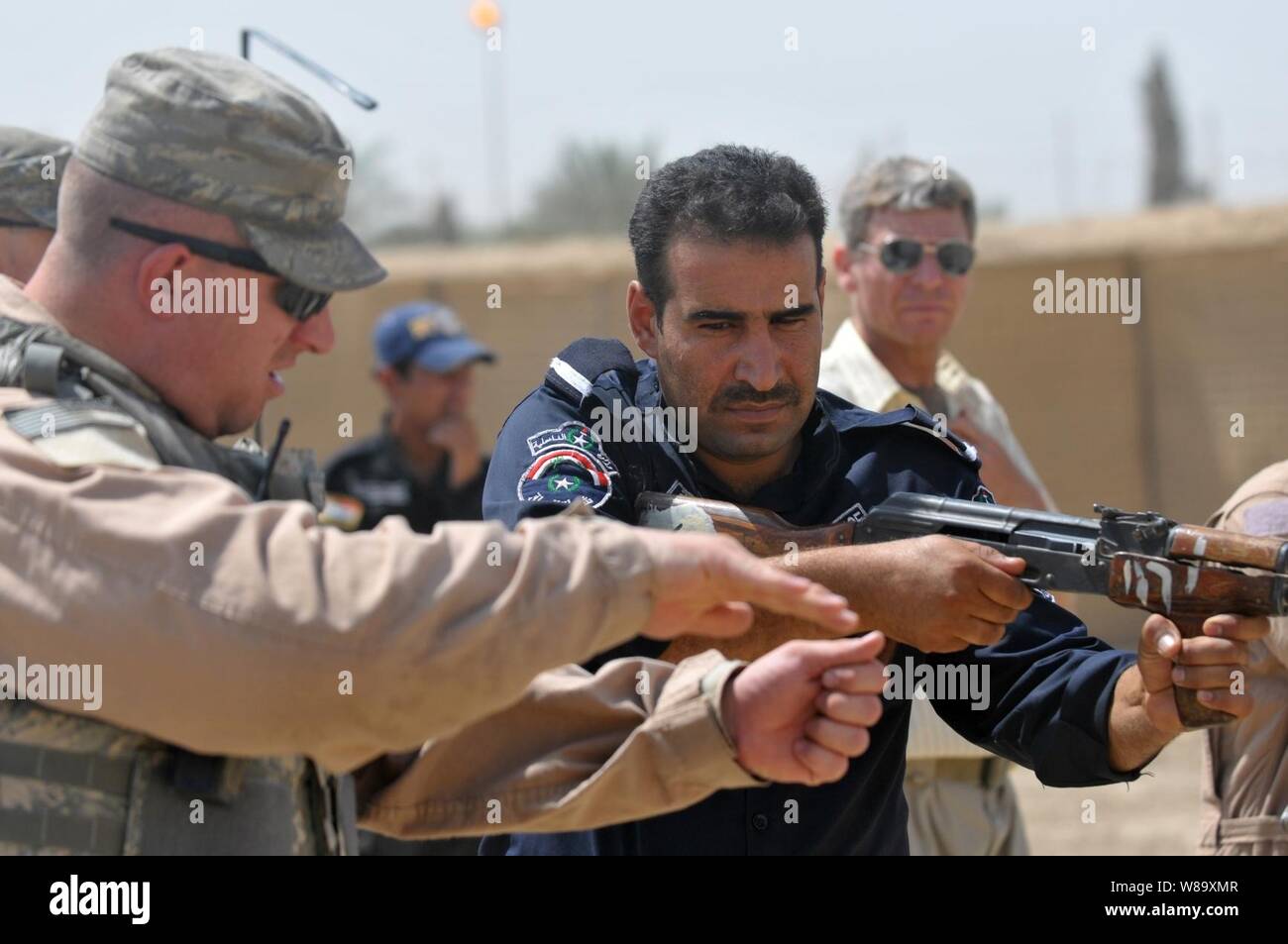 A U.S. Air Force airman with the 732nd Expeditionary Security Forces Squadron, attached to the 93rd Military Police Battalion, instructs an Iraqi Police officer from the Abu Ghraib district during range training at Forward Operating Base Mahmudiyah, Iraq, on July 8, 2009. Stock Photo
