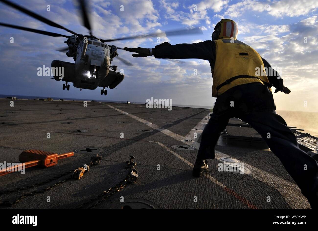 U.S. Navy Petty Officer 3rd Class Solomon Michel directs a U.S. Marine Corps CH-53E Sea Stallion helicopter as it approaches the flight deck of the amphibious dock landing ship USS Harpers Ferry (LSD 49) during touch-and-go landing qualifications in the South China Sea on Oct. 29, 2009.  The Harpers Ferry is part of the USS Denver (LPD 9) Amphibious Task Group, which is conducting fall patrol in the western Pacific Ocean with the embarked 31st Marine Expeditionary Unit. Stock Photo