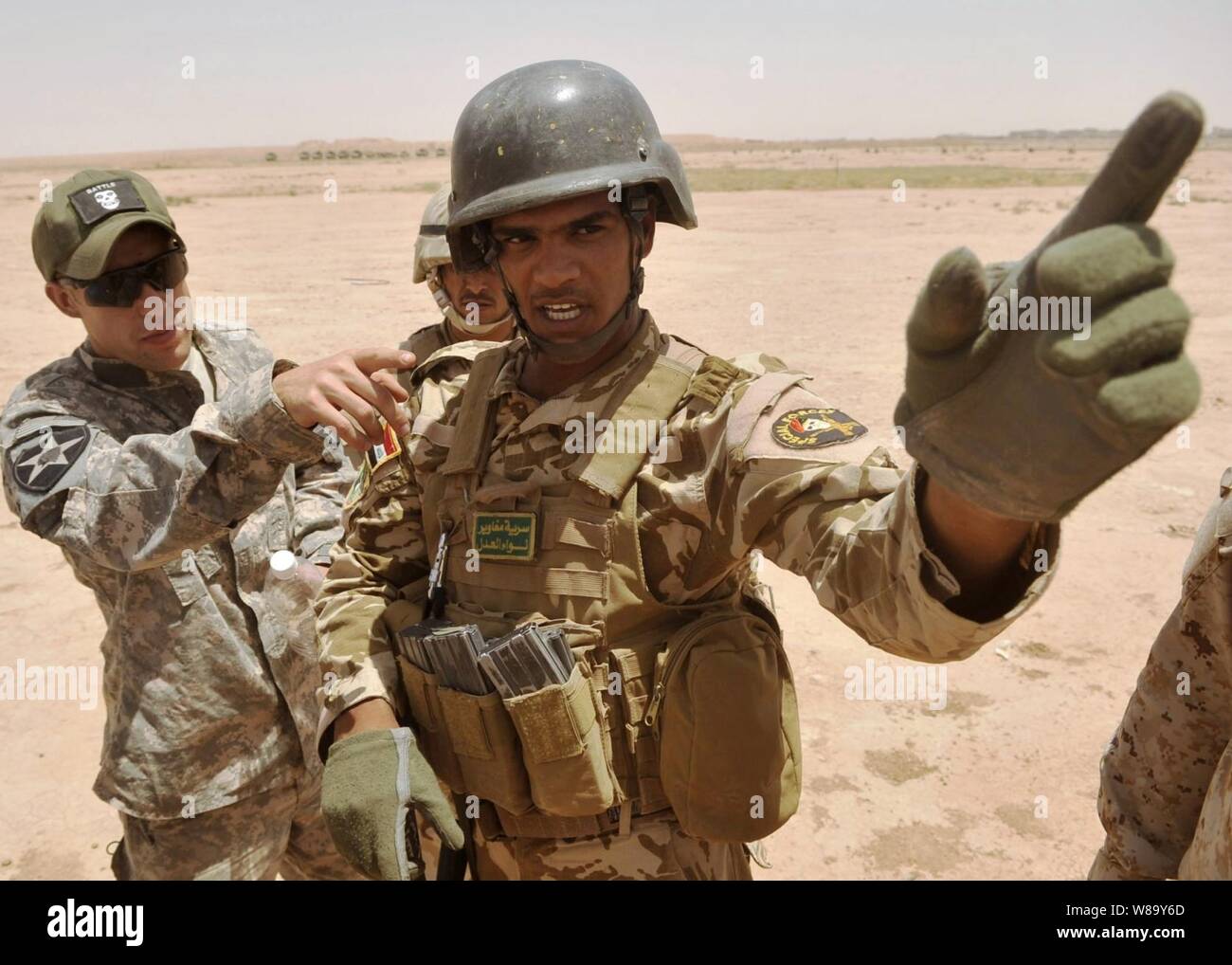 U.S. Army 1st Lt. J.D. Caddell (left), from Bravo Company, 5th Battalion, 20th Infantry Regiment, 3rd Stryker Brigade Combat Team, 2nd Infantry Division, discusses maneuvers with a team leader from the Iraqi Commando Battalion, 18th Brigade before a squad live-fire exercise at Kirkush Military Training Base, Diyala province, Iraq, on June 27, 2010. Stock Photo