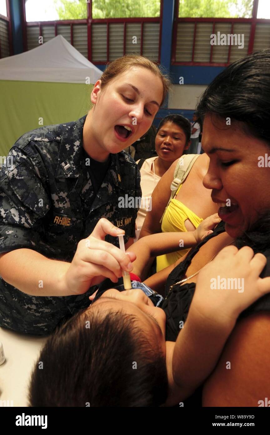 U.S. Navy Lt. j.g. Katt Rhine gives deworming medication to an infant ...