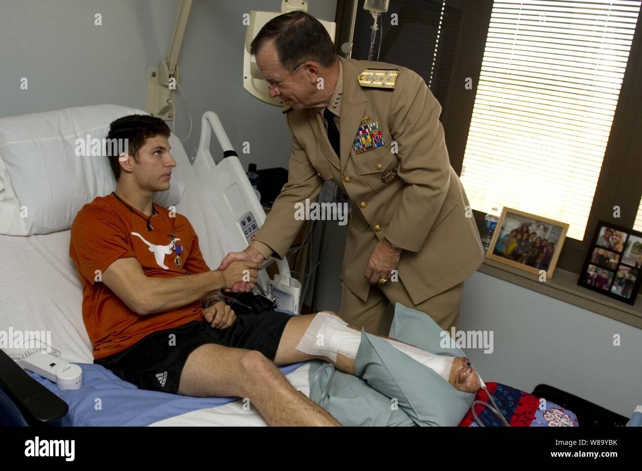 Chairman of the Joint Chiefs of Staff Adm. Mike Mullen, U.S. Navy, presents U.S. Army Spc. David R. Reid III with the Purple Heart during a visit to Brooke Army Medical Center in San Antonio, Texas, on Sept. 30, 2010.  Reid, a Ranger assigned to the 75th Ranger Regiment, sustained his injuries on Sept. 20 when he stepped on a pressure plate improvised explosive device during combat operations in Afghanistan. Stock Photo