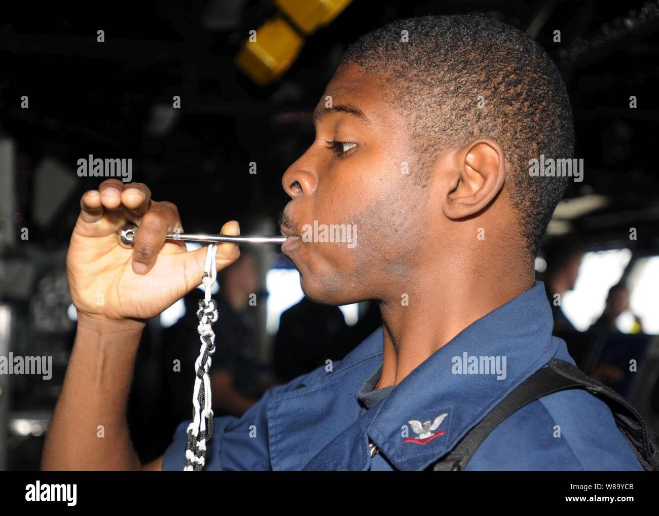 U.S. Navy Boatswain's Mate 3rd Class Aaron Shorts pipes the mess call into the main public address circuit aboard the amphibious assault ship USS Peleliu (LHA 5) underway in the north Arabian Sea in support of disaster relief operations in Pakistan on Sept. 4, 2010. Stock Photo
