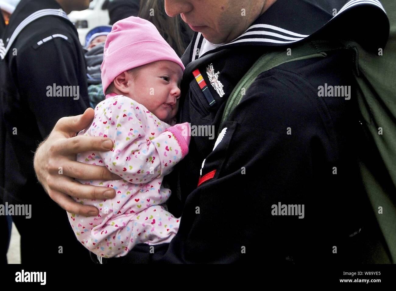 U.S. Navy Petty Officer 3rd Class Matthew Sandlin holds his newborn daughter for the first time after being underway for six months aboard the aircraft carrier USS George Washington (CVN 73) in the Pacific Ocean at Yokosuka, Japan, on Nov. 1, 2010.  Sandlin is assigned as a machinist's mate. Stock Photo