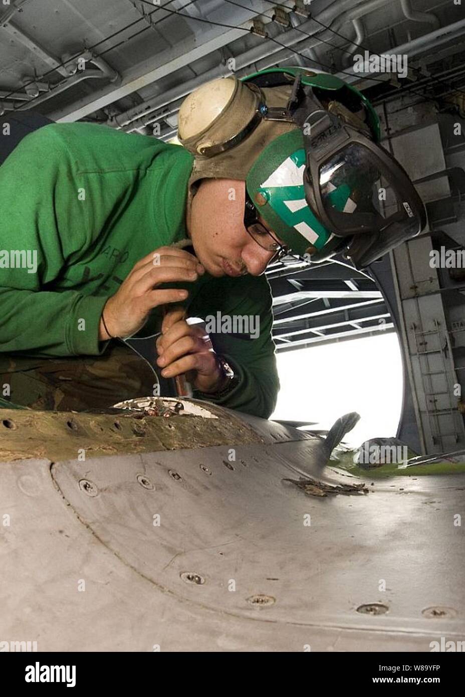 Petty Officer 3rd Class Luke Spataro performs corrosion control on an F/A-18E Super Hornet aboard the aircraft carrier USS George Washington (CVN 73) in the Pacific Ocean on Nov. 26, 2010.  The George Washington is on patrol in the western Pacific Ocean helping to ensure security and stability. Stock Photo
