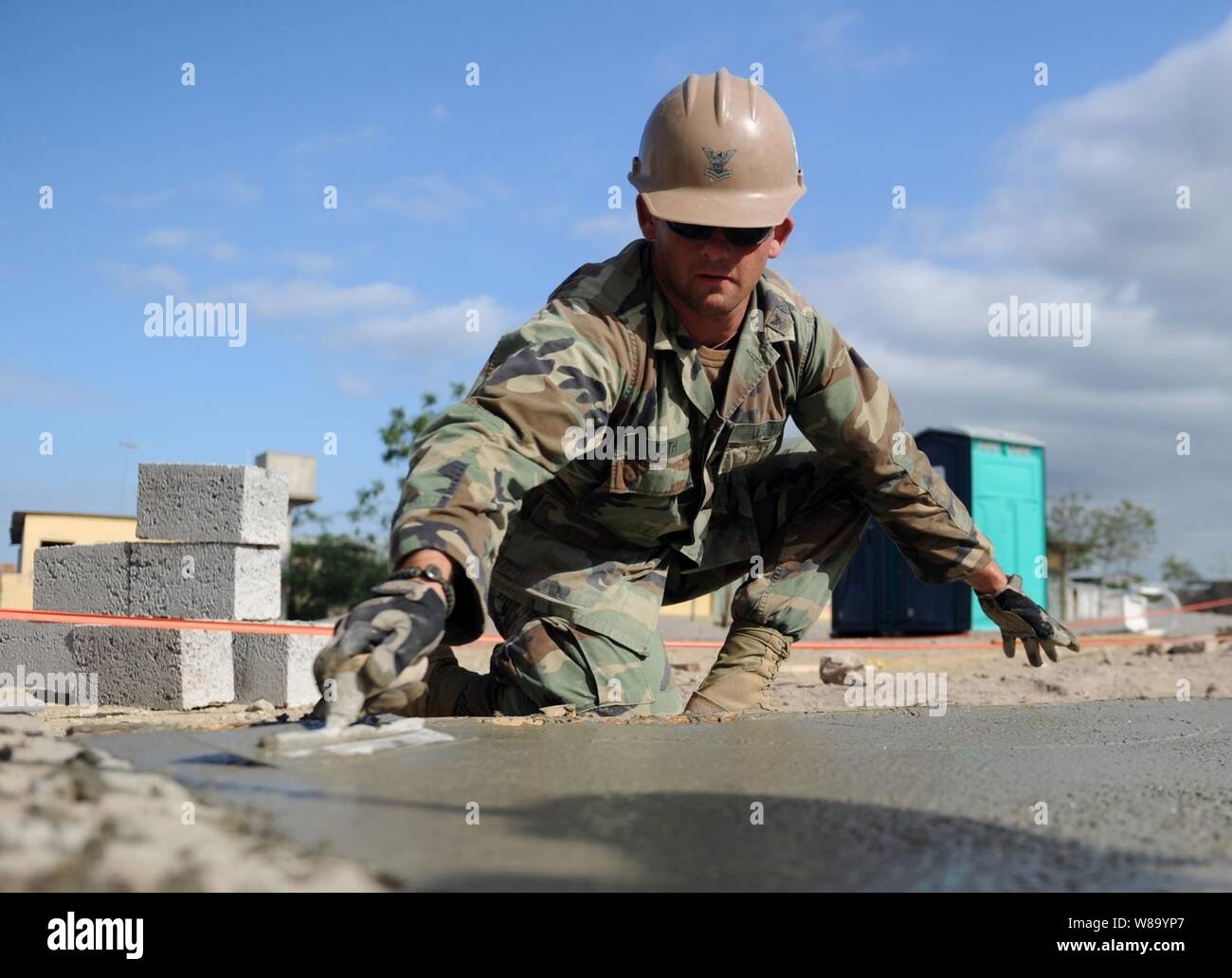 U.S. Navy Petty Officer 2nd Class Andras Toth, assigned to Naval Mobile Construction Battalion 28, trowels the foundation of a new classroom being built at the Jacobo Vera school in Manta, Ecuador, during Southern Partnership Station 2011 on Jan. 11, 2011.  Southern Partnership Station was a deployment of specialty platforms to the U.S. Southern Command area of responsibility in the Caribbean and Central America.  The mission's primary goal was information sharing with navies, coast guards and civilian services throughout the region. Stock Photo