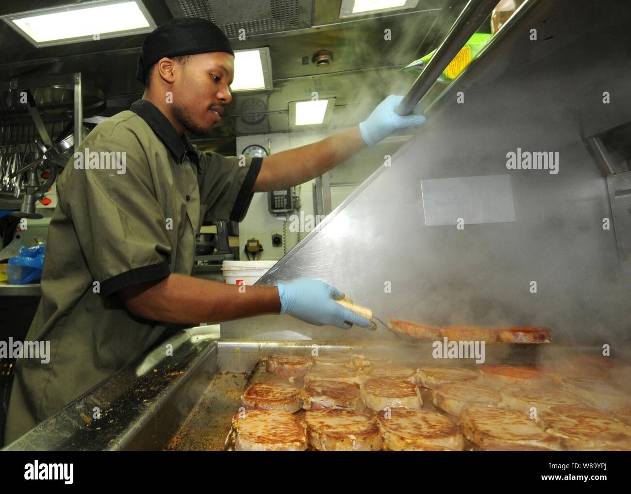 Seaman Diante A. Johnson prepares pork chops in the ship's galley for the crew aboard the guided-missile cruiser USS Anzio (CG 68) underway in the Pacific Ocean on Jan. 24, 2011. Stock Photo
