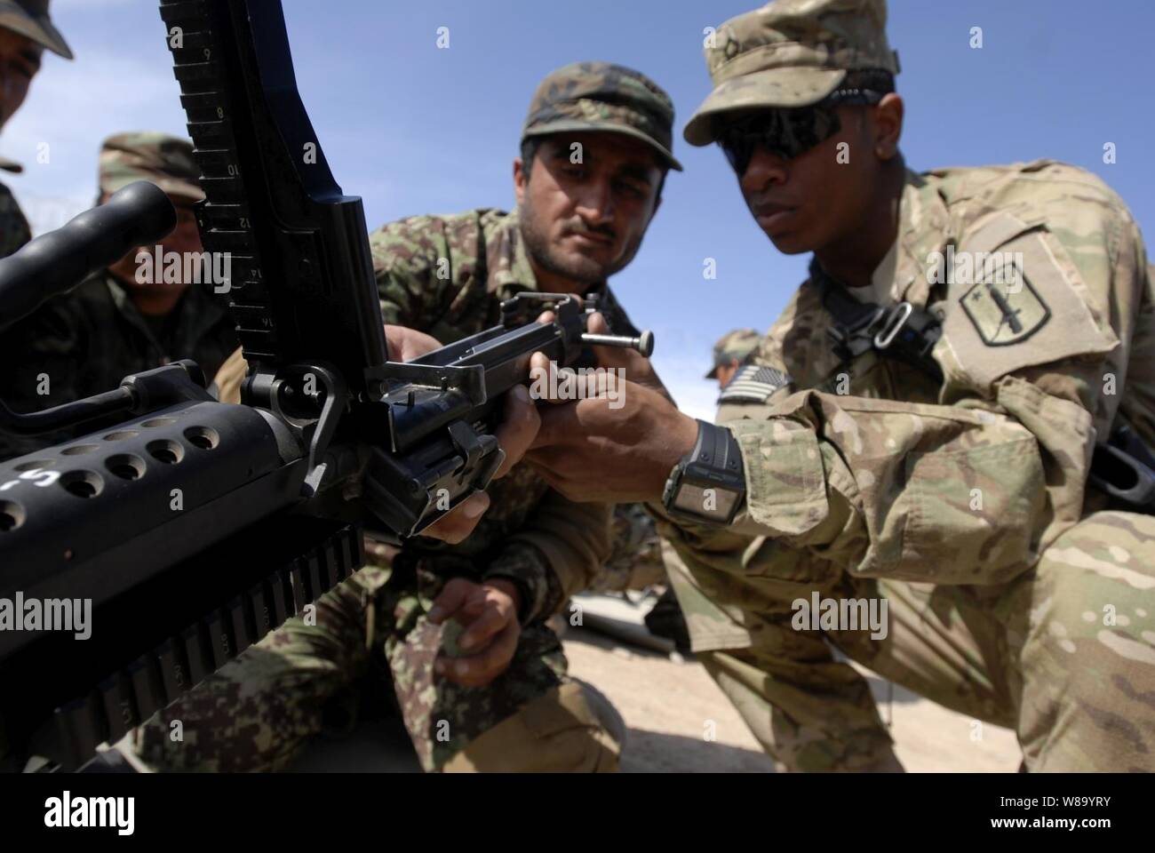 U.S. Army Pfc. Jeremiah Jones (right), with Bravo Company, 3rd Battalion, 4th Infantry Regiment, 170th Infantry Brigade, shows an Afghan National Army recruit how to disassemble a M240B machine gun during weapons training at Basic Warrior Training at Regional Military Training Center, Kandahar province, Afghanistan, on Feb. 22, 2011.  The recruits performed basic maintenance skills on these weapons before taking them to a weapons range. Stock Photo