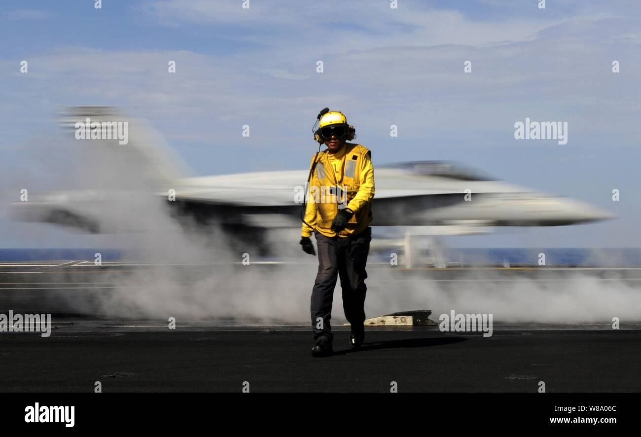 Petty Officer 2nd Class Jason Querido, assigned to the air department of the aircraft carrier USS Carl Vinson (CVN 70), works as an aircraft director on the flight deck in the Pacific Ocean on May 13, 2011.  The Carl Vinson and Carrier Air Wing 17 are underway in the U.S. 7th Fleet area of responsibility. Stock Photo