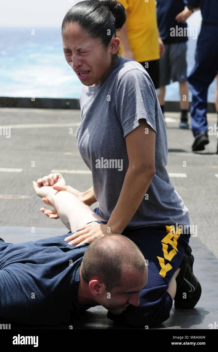 Petty Officer 2nd Class Jaqueline Rodriguez subdues a simulated suspect after being sprayed with oleoresin capsicum spray, also known as pepper spray, during security training aboard the amphibious dock landing ship USS Comstock (LSD 45) in the Gulf of Aden on May 10, 2011.  The Comstock is underway supporting maritime security operations and theater security cooperation efforts in the U.S. 5th Fleet area of responsibility. Stock Photo