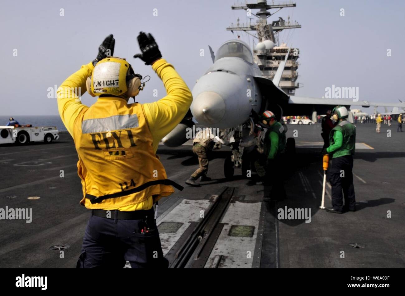 Petty Officer 3rd Class Patrick Wight signals to the pilots of an F/A-18 aircraft before launching off the flight deck of the aircraft carrier USS Ronald Reagan (CVN 76) in the Arabian Sea on June 6, 2011.  The Ronald Reagan and Carrier Air Wing 14 are deployed to the U.S. 5th Fleet area of responsibility conducting close-air support missions as part of Operation Enduring Freedom. Stock Photo