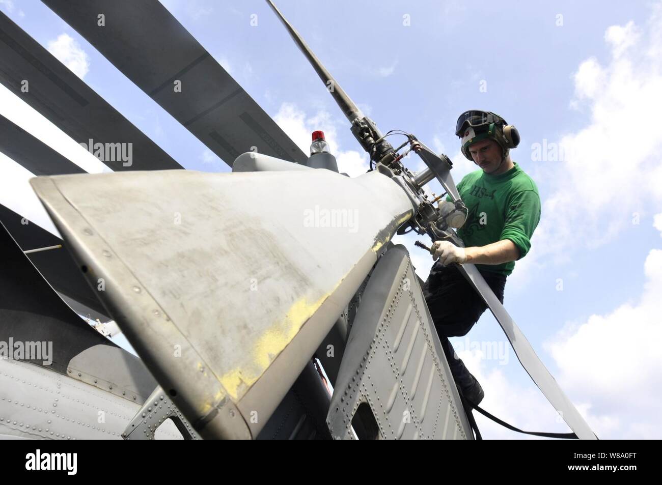 U.S. Navy Petty Officer 2nd Class Branden Rucker performs maintenance to control corrosion on the tail rotor of an SH-60F Seahawk helicopter assigned to Helicopter Anti-Submarine Squadron 4 aboard the aircraft carrier USS Ronald Reagan (CVN 76) in the South China Sea on Aug. 9, 2011.  The Ronald Reagan is underway in the U.S. 7th Fleet area of responsibility. Stock Photo