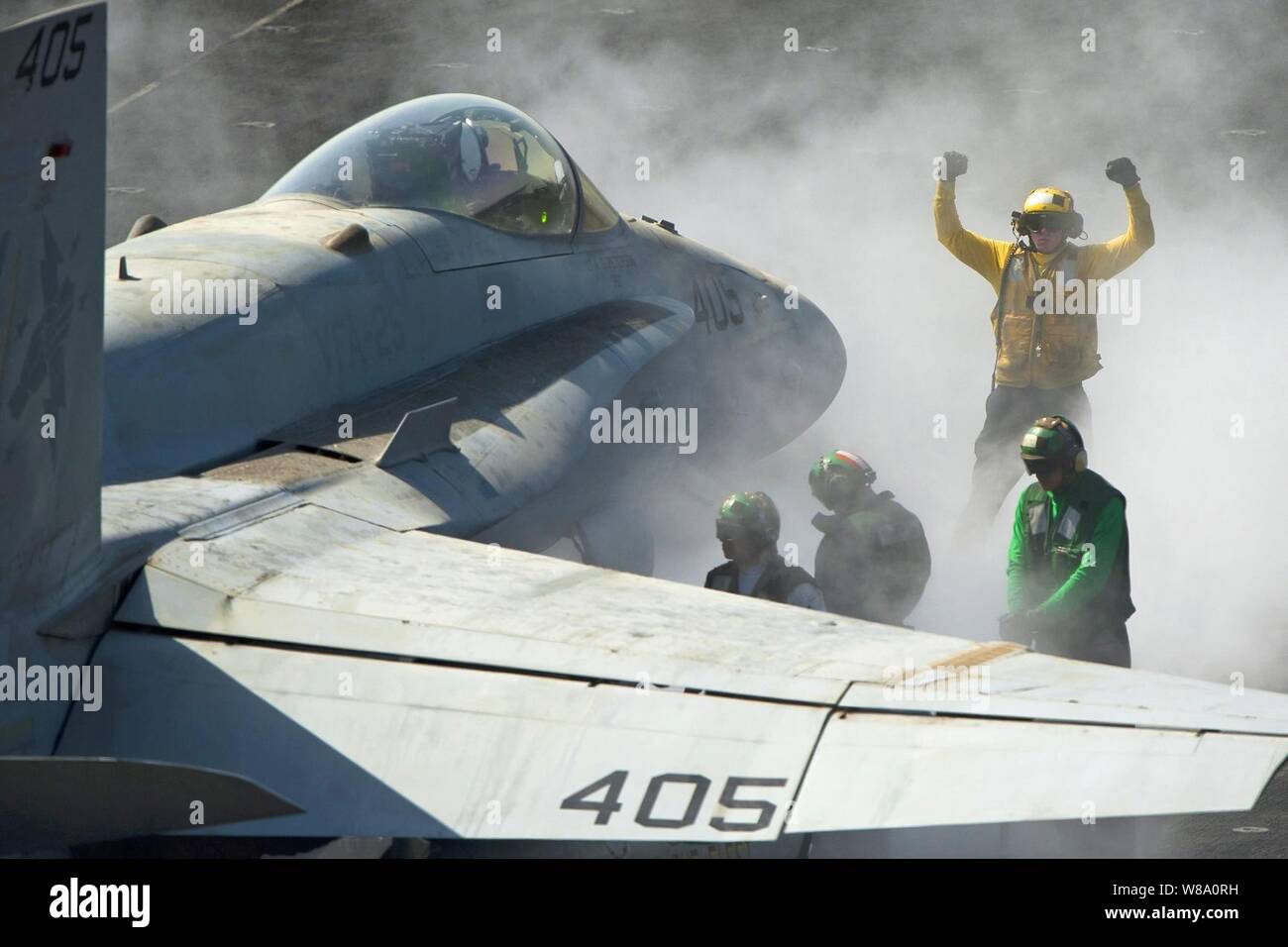 U.S. Navy Petty Officer 3rd Class Eric Welsh directs an F/A-18C Hornet onto the bow catapults for launch on the flight deck aboard the aircraft carrier USS Carl Vinson in the Persian Gulf on March 5, 2012.  Welsh is an aviation boatswain's mate, handling. Stock Photo
