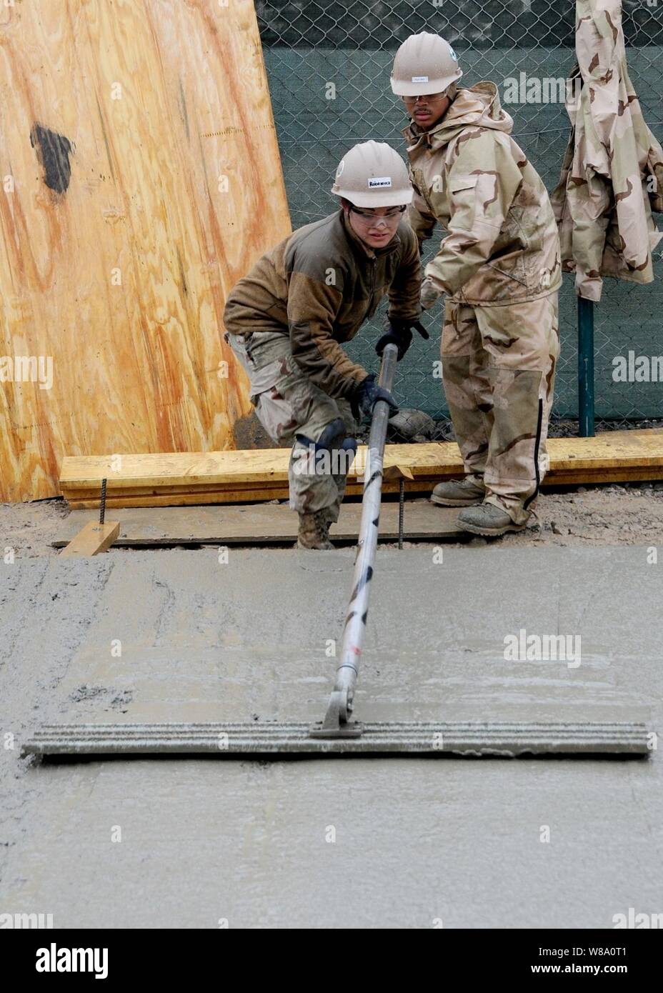 Petty Officer Selina Rodriguez, assigned to Naval Mobile Construction Battalion 7, uses a bull float to finish concrete at Kandahar Airfield on Feb. 17, 2012.  Naval Mobile Construction Battalion 7 and its detachments are one of two Seabee battalions supporting the International Security Assistance Force as part of Task Force Stethem, operating in the U.S. Central Command area of responsibility. Stock Photo