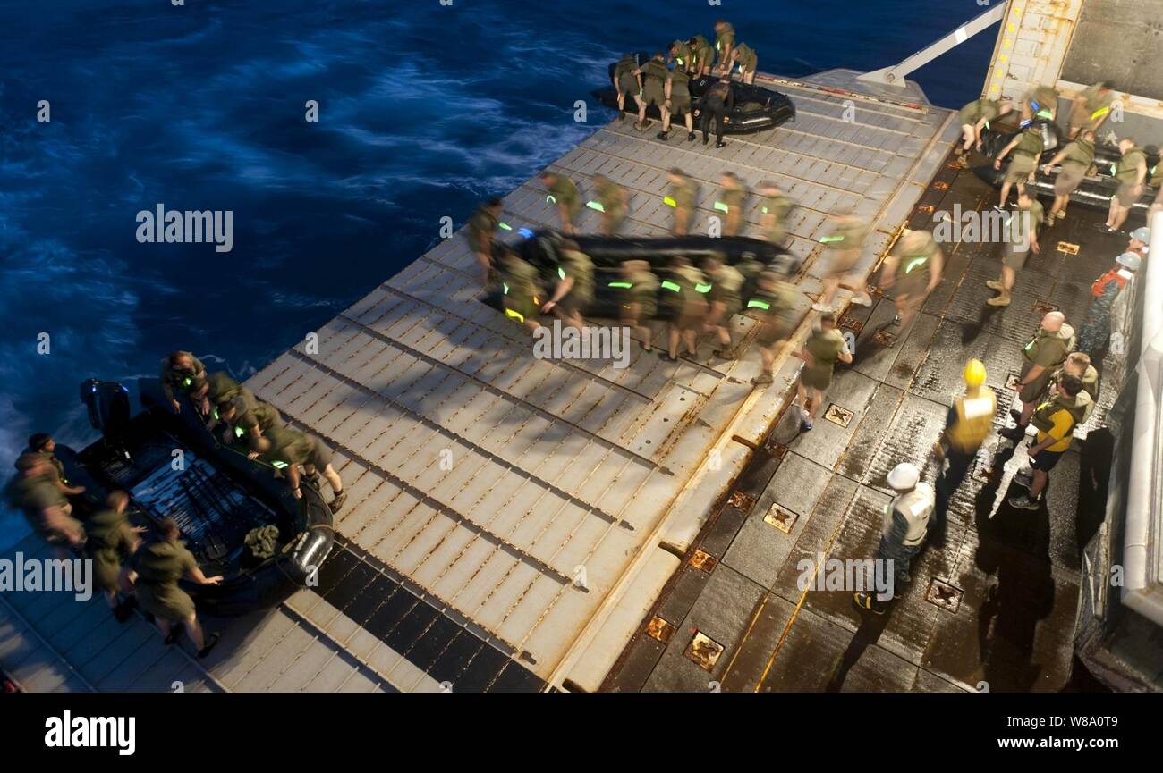 Marines from the 31st Marine Expeditionary Unit carry a combat rubber raiding craft to the stern gate of the forward-deployed amphibious dock landing ship USS Tortuga (LSD 46) during a night exercise in the Pacific Ocean on March 1, 2012.  The Tortuga, part of the Essex Amphibious Readiness Group, is underway on deployment in the U.S. 7th Fleet area of responsibility. Stock Photo